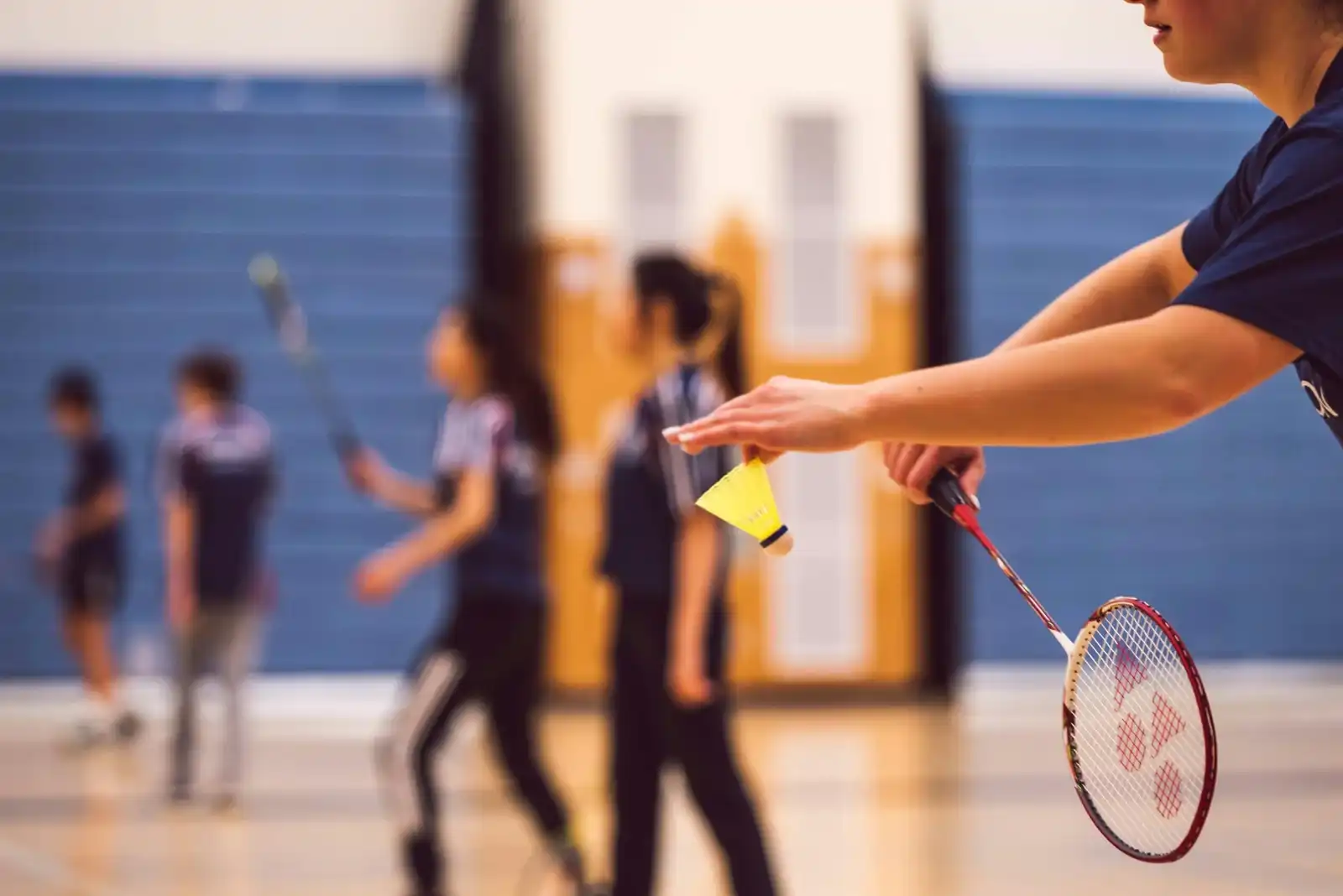 Participants staying active and social during Boswin’s indoor badminton sessions for adults.